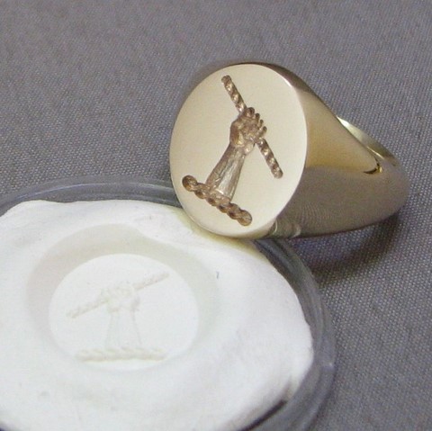 Hand holding scroll crest seal engraved