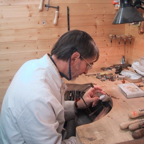 Jeweller at bench making signet rings